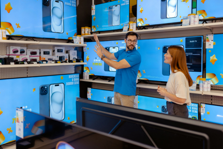 man and woman looking at TVs
